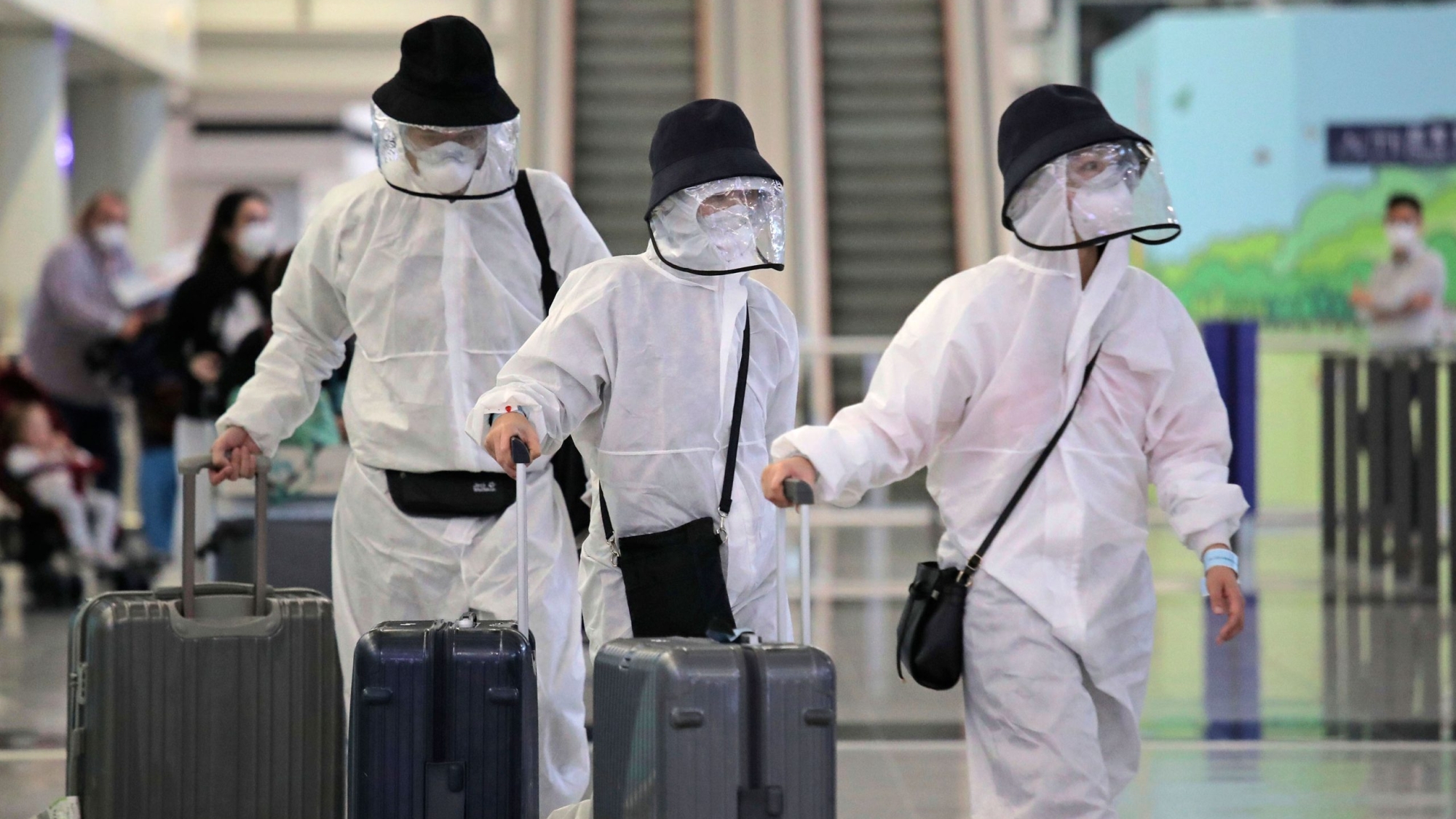 Passengers wear protective suits and face masks as they arrive at the Hong Kong airport, Monday, March 23, 2020. For most, the coronavirus causes only mild or moderate symptoms, such as fever and cough. But for a few, especially older adults and people with existing health problems, it can cause more severe illnesses, including pneumonia. (AP Photo/Kin Cheung)
