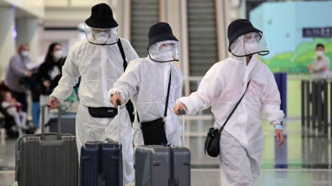 Passengers wear protective suits and face masks as they arrive at the Hong Kong airport, Monday, March 23, 2020. For most, the coronavirus causes only mild or moderate symptoms, such as fever and cough. But for a few, especially older adults and people with existing health problems, it can cause more severe illnesses, including pneumonia. (AP Photo/Kin Cheung)